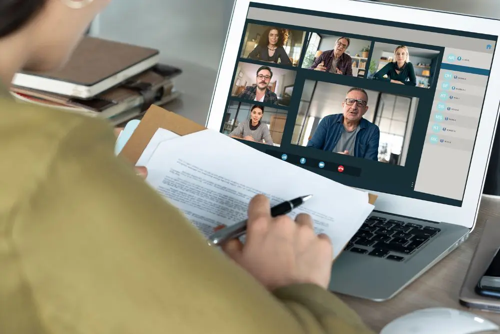 Someone in dark yellow sits at their laptop on a video call with 6 participants.